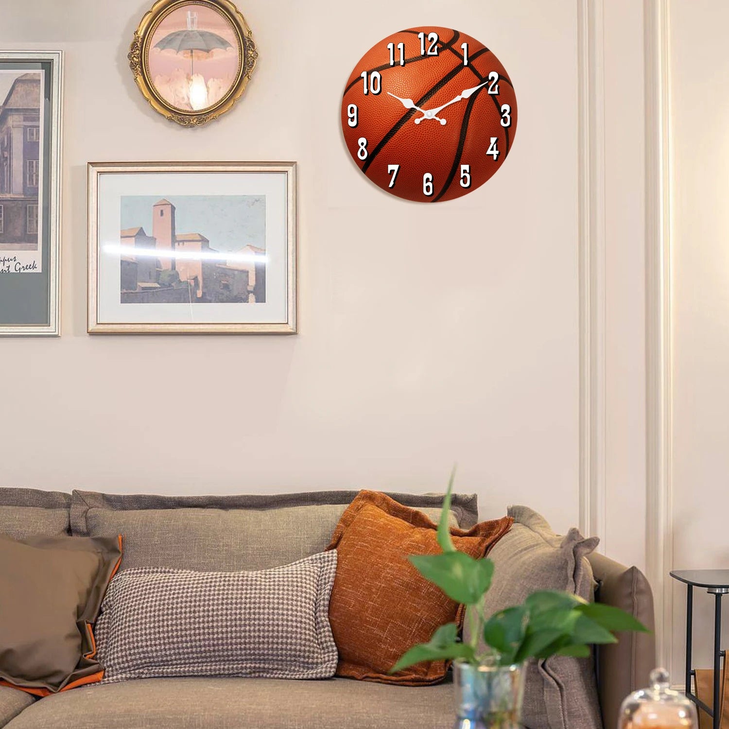 Basketball wall clock displayed above a living room sofa, featuring a realistic basketball design and silent quartz movement for stylish sports-themed home, office, or game room decor.